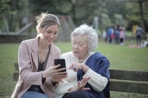 Daughter and elder mom sitting on park bench 