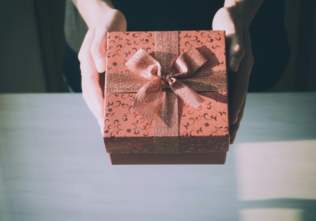 someone holding a rose gold colored gift box with a matching bow