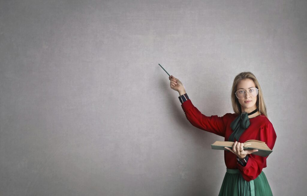 woman holding a book, pointing to a blank board