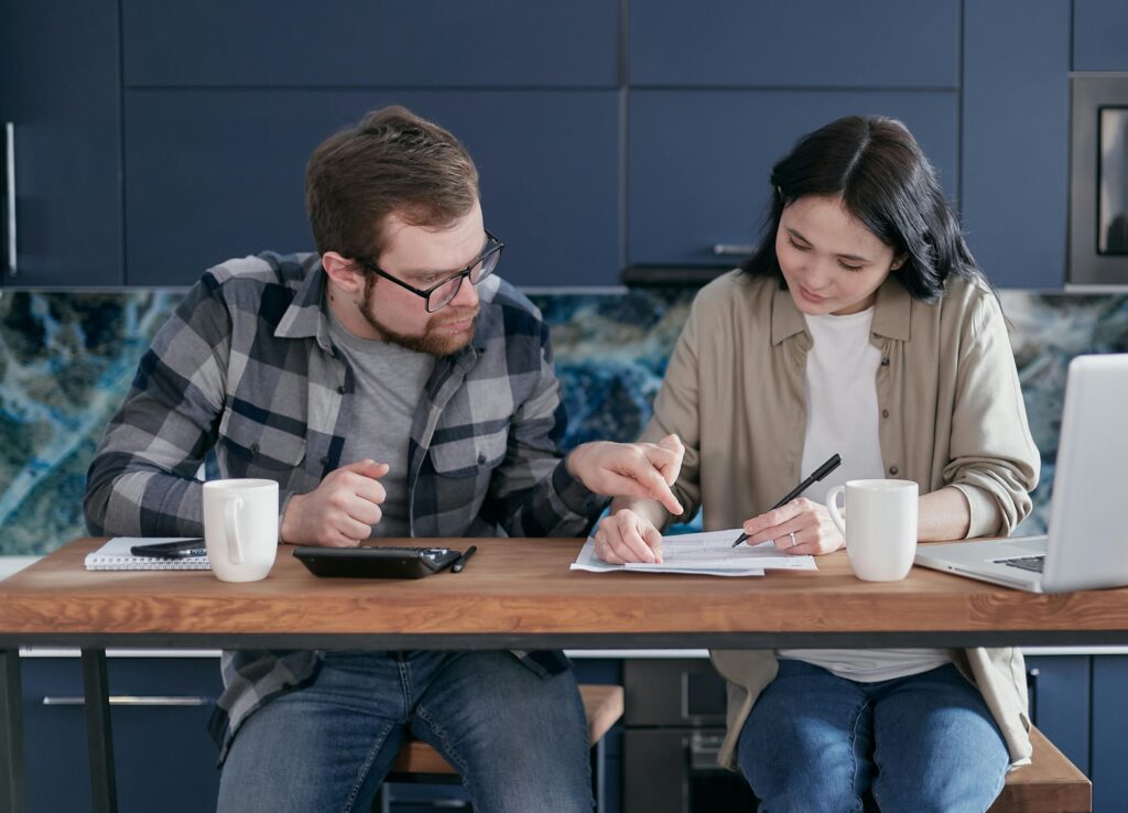 man and woman sitting at table reviewing paperwork. 