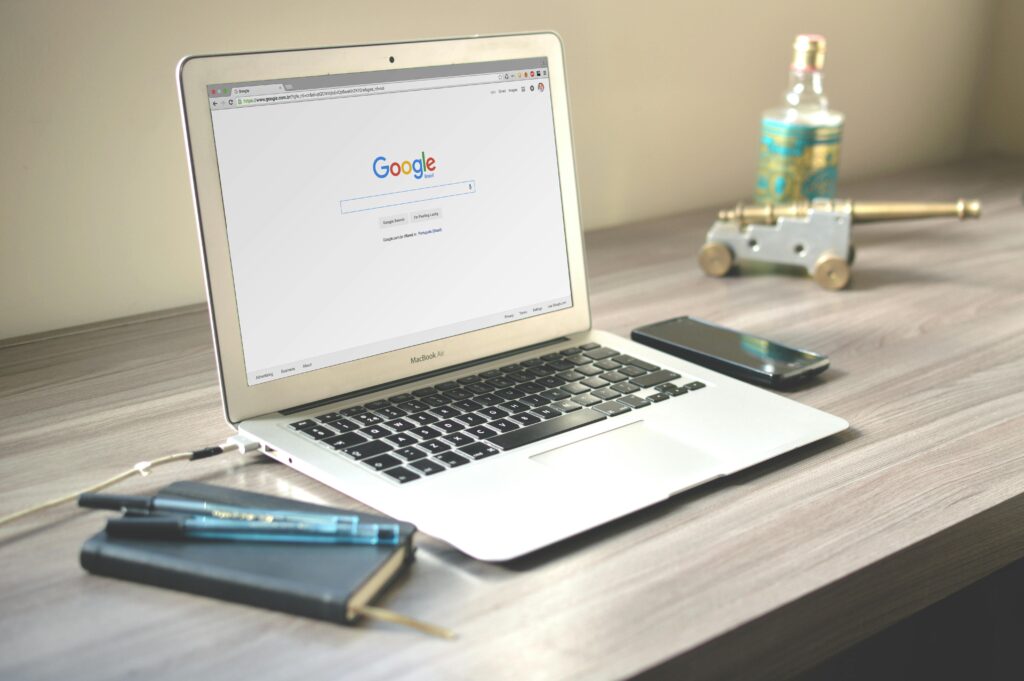 . Open laptop on a table. The screen shows an image of the google search bar. 