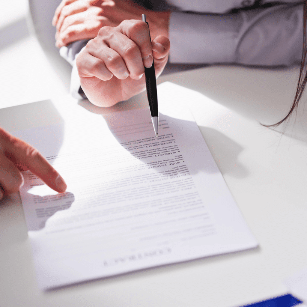 image of a paper with writing on it. 2 sets of hands, one pointing tot he paper, the other holding a pen pointing to the paper. 